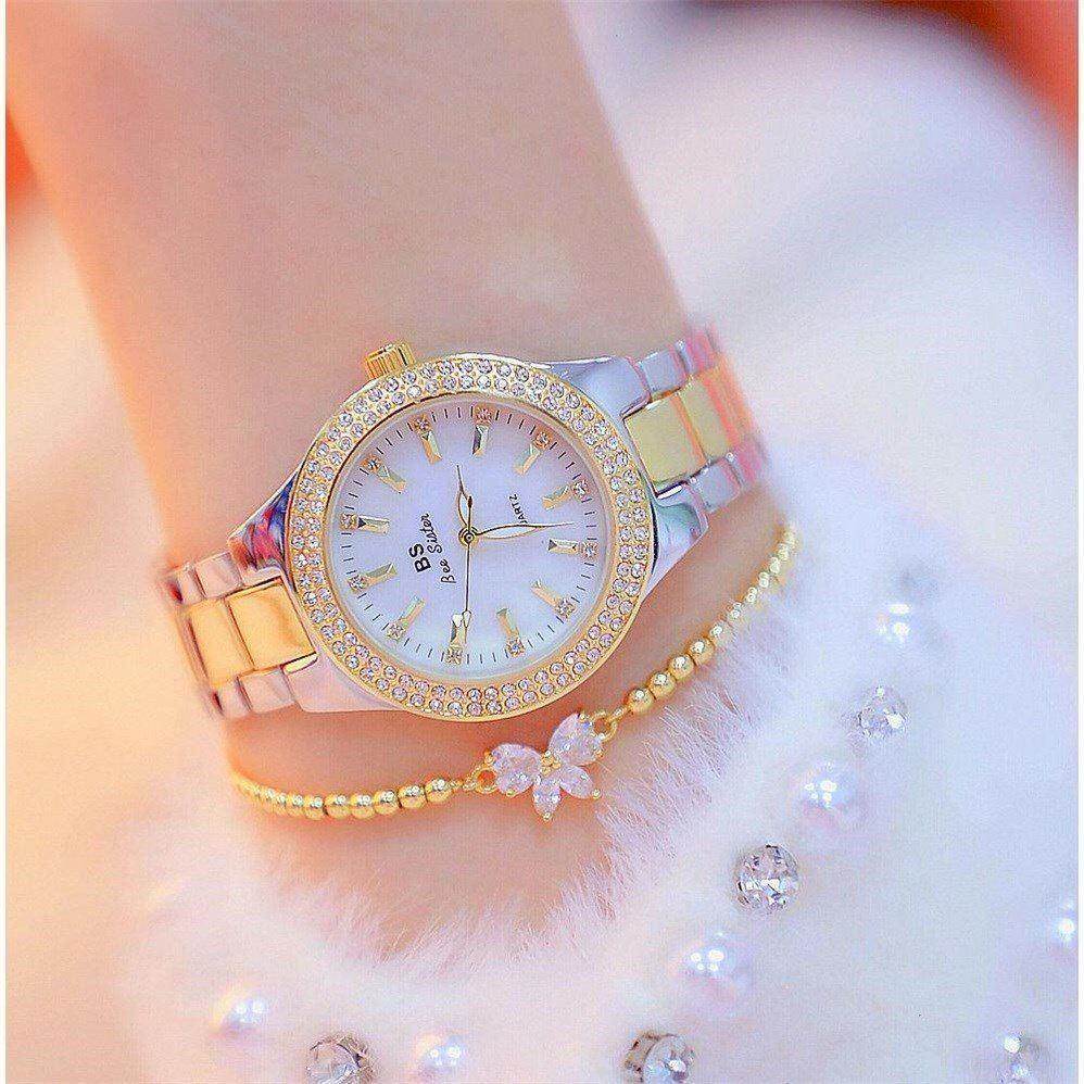 Mechanical watch with white ceramic dial and gold accents on a female wrist with bow bracelet.