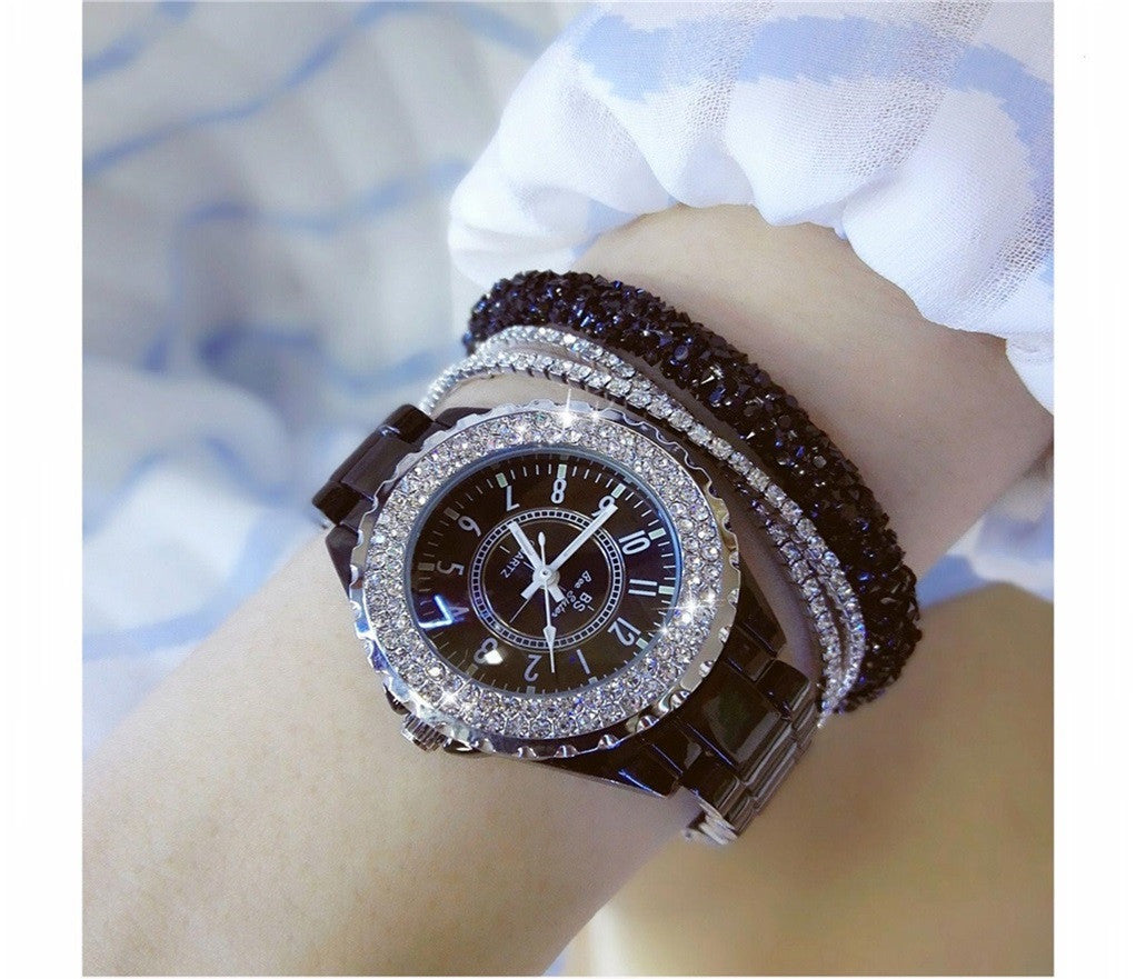 Mechanical watch with black ceramic bracelet on wrist.