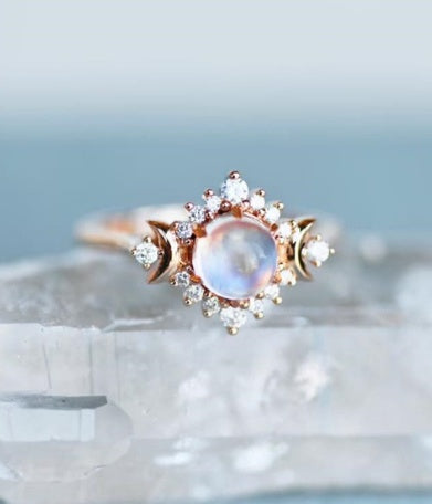 Fashion ring with moonstone and intricate gold detailing on display.