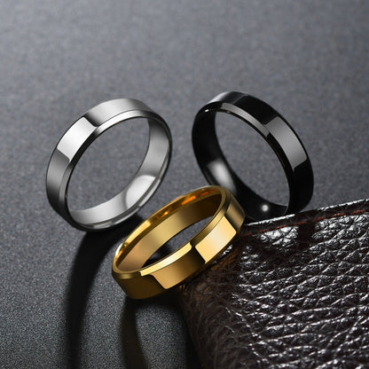 Stainless steel couple rings for women in steel, black, and gold colors on a textured surface.