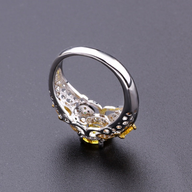 Alloy geometric zircon ring with intricate detailing and yellow stone on dark background.