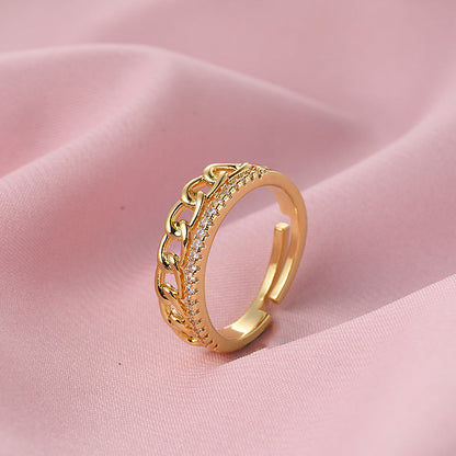 Versatile gold copper ring with chain design on pink fabric background.