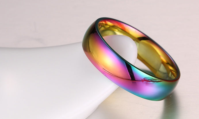 Stainless steel rainbow ring with vibrant multicolour finish on light background.