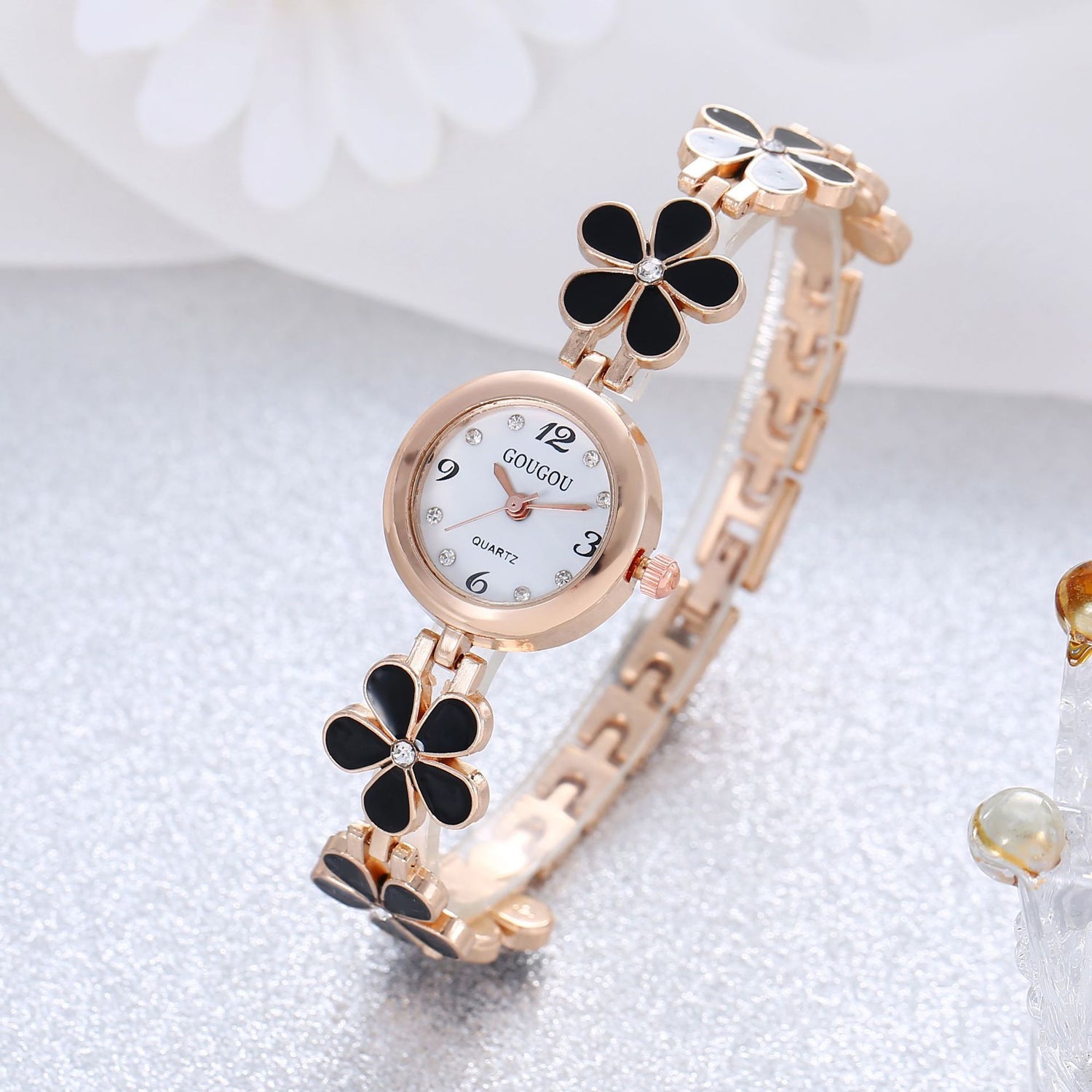 Ladies petal patterned quartz watch and bracelet set on a textured surface.